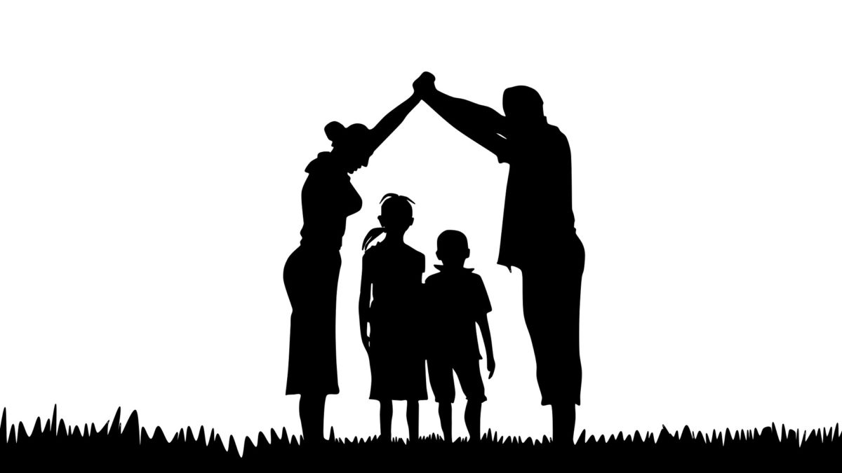 Silhouette einer Familie. Mann und Frau bilden mit ihren Armen ein Dach über zwei Kindern.