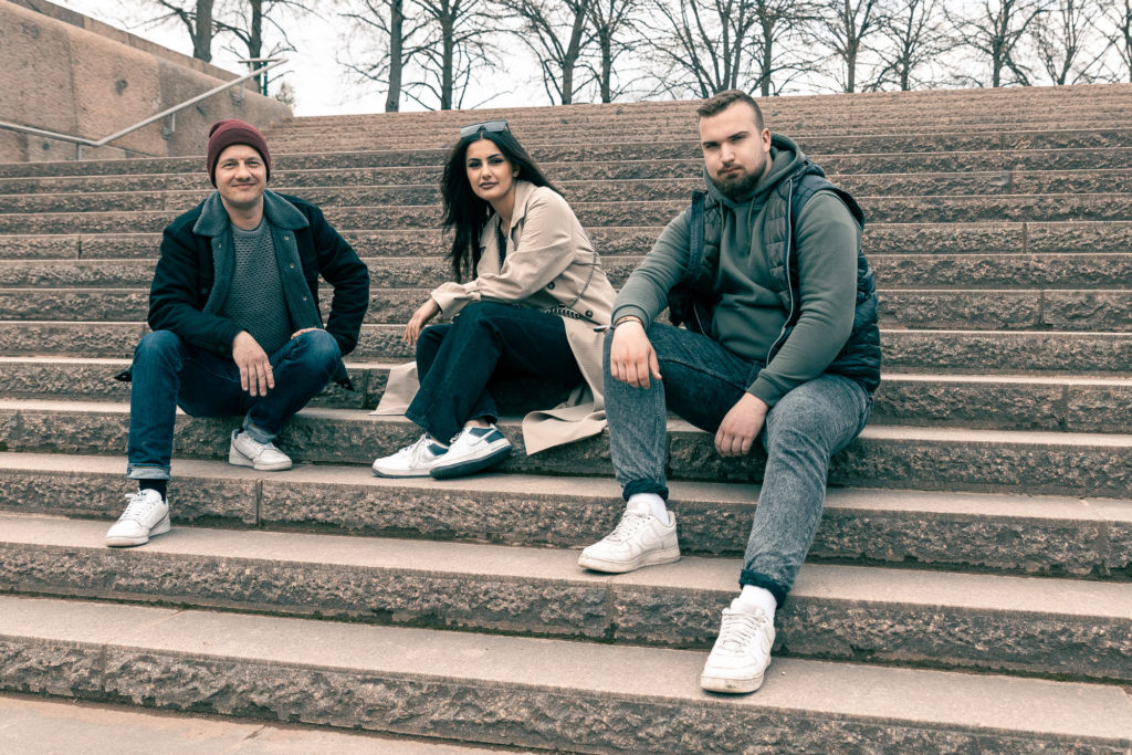 Drei junge Menschen sitzen auf einer Treppe im Freien.
